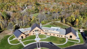 The Greylock Glen Center photographed from an aerial drone from above the parking lot looking West toward the woods behind the building